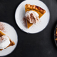 Slices of pumpkin pie topped with whipped cream and spices, viewed from above